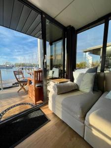 sala de estar con sofá y vistas al agua en Huisboot Comfort M Plus Limburg, en Kinrooi