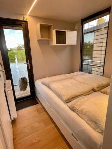 Habitación pequeña con 2 camas y ventana en Huisboot Comfort M Plus Limburg, en Kinrooi
