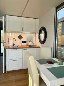 una cocina con armarios blancos y una mesa con un bol de fruta en Huisboot Comfort M Plus Limburg, en Kinrooi