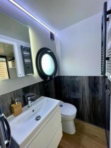 a bathroom with a white sink and a toilet at Huisboot Comfort M Plus Limburg in Kinrooi