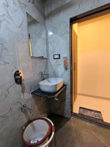 a bathroom with a sink and a toilet and a mirror at Sharan Residency in Navi Mumbai
