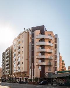 a tall apartment building with cars parked in front of it at Hotel Madanis in Hospitalet de Llobregat