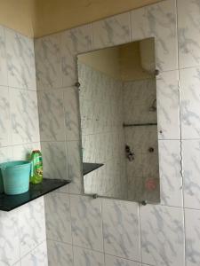 a mirror on a tiled wall in a bathroom at Suite with an airy rooms in Kānpur