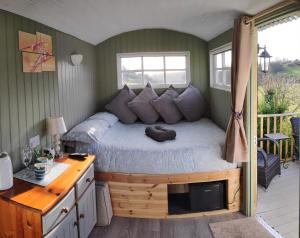 a bedroom with a bed with a desk and a window at Shepherds hut in Weymouth