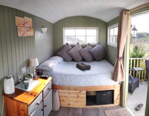 a bedroom with a bed with a desk and a window at Shepherds hut in Weymouth