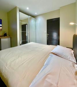 a bedroom with a large white bed with a mirror at L'Eskale Guyane in Montjoly