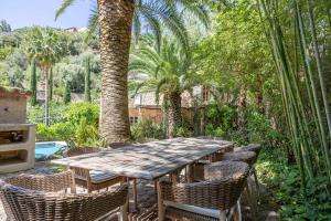 a wooden table and chairs in a garden with palm trees at ES CLOT in Deia