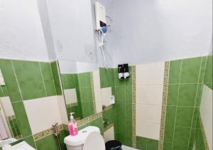 a green and white bathroom with a toilet and a shower at Small Apartment Near SM North Project 7 in Manila