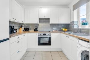 a white kitchen with white cabinets and a dishwasher at Lark Rise Lodge in Brackley
