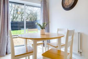 a dining room table and chairs with a clock on the wall at Lark Rise Lodge in Brackley