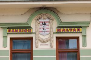 a sign on the side of a building with two doors at Pansion Maltar Varaždin in Varaždin