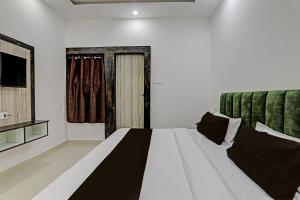 a bedroom with a large white bed and a television at OYO Flagship THE VINDH in Gorakhpur