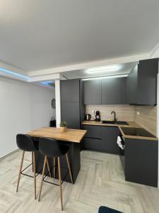 eine Küche mit einem Holztisch und schwarzen Schränken in der Unterkunft Sunny Apartments Avanera Suceava in Suceava