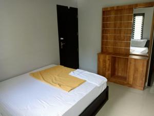 a bedroom with a bed with a yellow blanket on it at MALANAD GUEST HOUSE THENGIPALAM CHENAKAL UNIVERCITY ROAD 