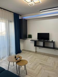 ein Wohnzimmer mit einem Tisch und einem TV in der Unterkunft Sunny Apartments Avanera Suceava in Suceava