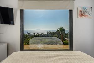 a bedroom with a large window looking out at the ocean at Cala Salada Sunset View in San Antonio +27 photos