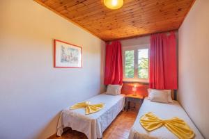 two beds in a room with red curtains and a window at Escalante C8 2 in Cala'n Bosch +15 photos