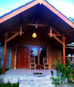 uma casa com uma grande porta de madeira e duas cadeiras em Green Haven Homestay em Tetebatu