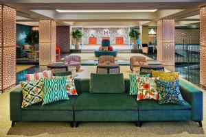 a green couch with colorful pillows in a lobby at Hesperia Sevilla in Seville