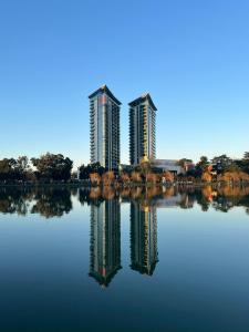 dwa wysokie budynki znajdują odbicie w jeziorze w obiekcie Bellevue Residence Suites w mieście Batumi