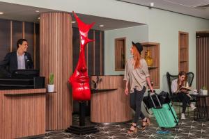 a woman walking through a lobby with luggage and a red vase at Ibis Marrakech Centre Gare in Marrakesh