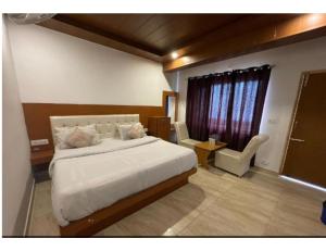 a bedroom with a large white bed and a window at Hotel Atithi, Near Yes Bank, Mall Road, Mussoorie in Mussoorie
