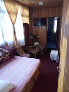 een slaapkamer met een bed, een tafel en een deur bij Darjeeling Inn , Darjeeling in Darjeeling