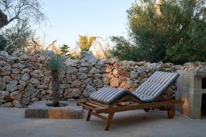 una silla de madera sentada junto a una pared de piedra en Il Cubetto- a cute mini house in olive grove, en Surano