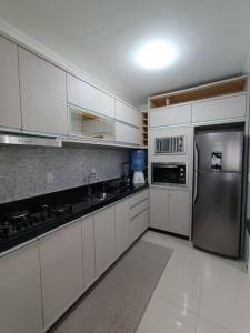 a kitchen with white cabinets and a stainless steel refrigerator at Vista mar com ótima localização na meia praia in Itapema
