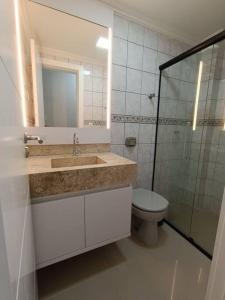 a bathroom with a sink and a toilet and a mirror at Vista mar com ótima localização na meia praia in Itapema