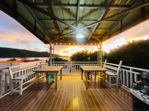a deck with two tables and a sunset on a boat at Zenhouse Calayo in Nasugbu