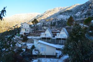 un pueblo con casas cubiertas de nieve y una montaña en Vinyasa Resort , Kanatal, en Kanatal