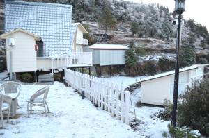 un patio cubierto de nieve con una valla y una casa en Vinyasa Resort , Kanatal, en Kanatal