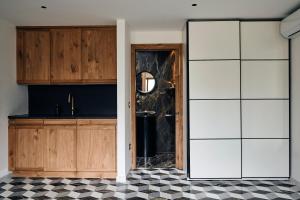 cocina con armarios de madera y suelo de baldosa blanco y negro en Il Cubetto- a cute mini house in olive grove, en Surano