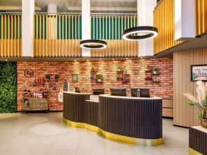 a lobby with desks and chairs and a brick wall at Novotel London Greenwich in London