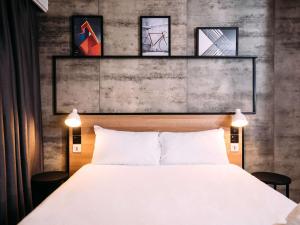 貝爾法斯特的住宿－宜必思貝爾法斯特市中心酒店，一间卧室配有一张床,墙上挂着一些图片