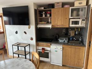 a small kitchen with white appliances and a table at Risoul duplex 48m2 avec piscine et sauna in Risoul