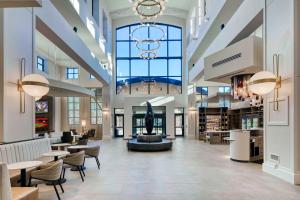 a large lobby with chairs and tables and windows at Embassy Suites by Hilton Raleigh Durham Airport Brier Creek in Raleigh