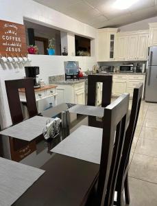 a kitchen with white cabinets and a table with chairs at Hostal Rio Piedra in Estelí