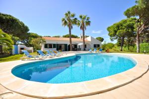 a swimming pool with chairs and a house at Close to amenities, free air conditioning and wi-fi in Quarteira