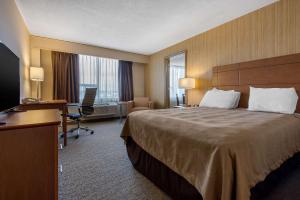 a hotel room with a large bed and a desk at Quality Inn & Conference Centre Downtown Sudbury in Sudbury
