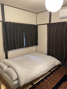 uma cama num quarto com cortinas pretas em KANJYAKU-AN - Vacation STAY 76347v em Nakatsugawa