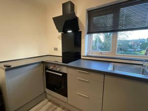 eine Küche mit einer schwarzen Arbeitsplatte und einem Waschbecken in der Unterkunft Burmer Central Bliss: Modern 3BR/1BA, Full Kitchen in Peterborough