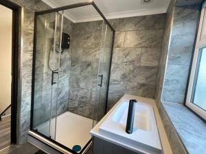 ein Bad mit einer Dusche und einem Waschbecken in der Unterkunft Burmer Central Bliss: Modern 3BR/1BA, Full Kitchen in Peterborough