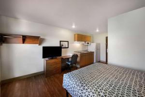 Mały pokój z łóżkiem, biurkiem i kuchnią. w obiekcie WoodSpring Suites Columbus Southeast w mieście Groveport