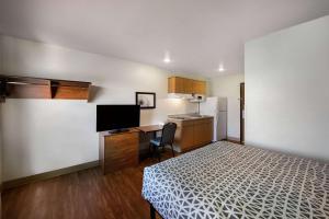 Cette petite chambre comprend un lit, un bureau et une cuisine. dans l'établissement WoodSpring Suites Columbus Southeast, à Groveport