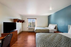a hotel room with two beds and a flat screen tv at WoodSpring Suites Columbus Southeast in Groveport