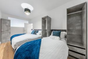 two beds in a room with white and blue at Modern Stylish 2 bedroom apartment in the heart of Potters Bar in Potters Bar