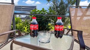 zwei Cola-Flaschen auf einem Tisch mit einem Glas in der Unterkunft Timeout -south Facing With Large Terrace And Pool in Cape Coral