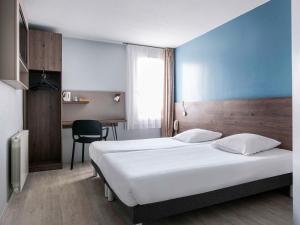 MassieuxにあるHOTEL Lyon Nord Massieux Genayのベッドとデスクが備わるホテルルームです。